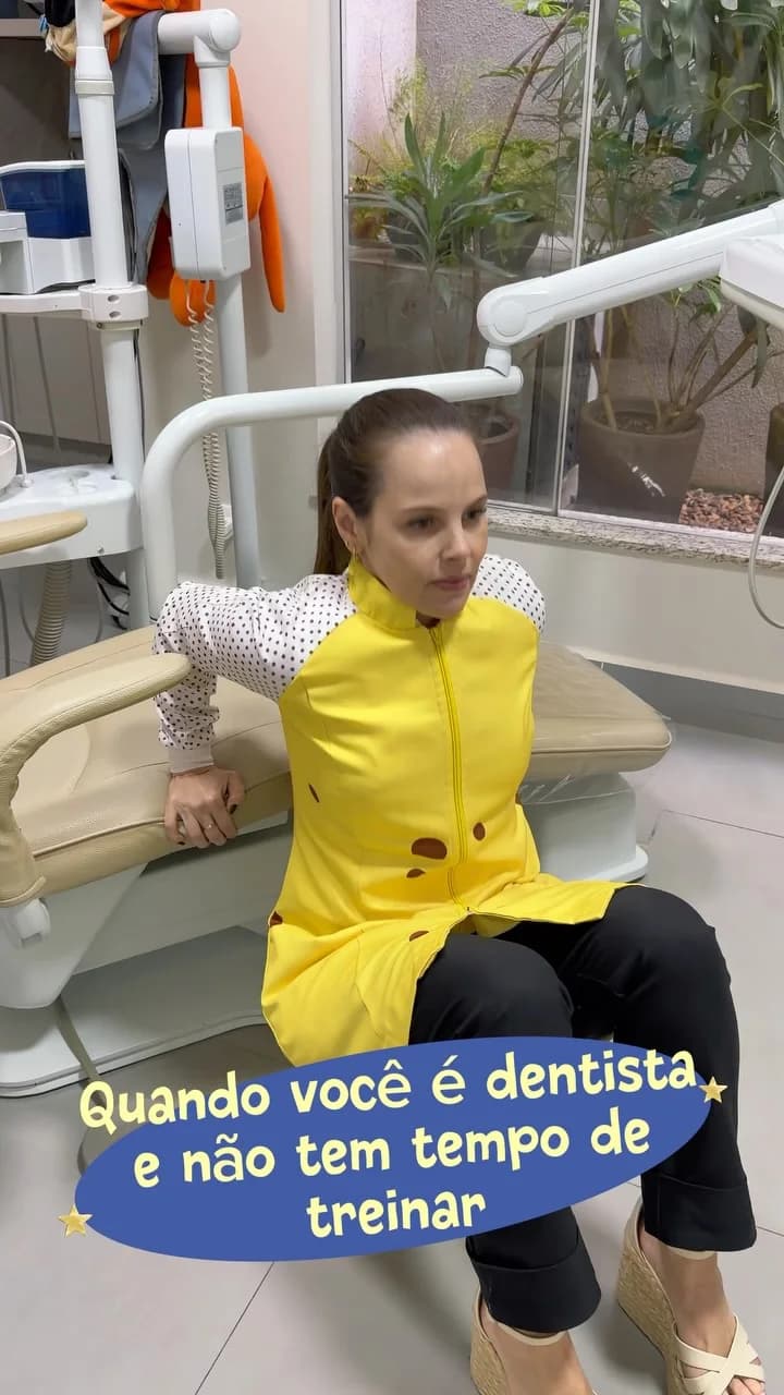 Profissional com jaleco amarelo no consultório odontológico